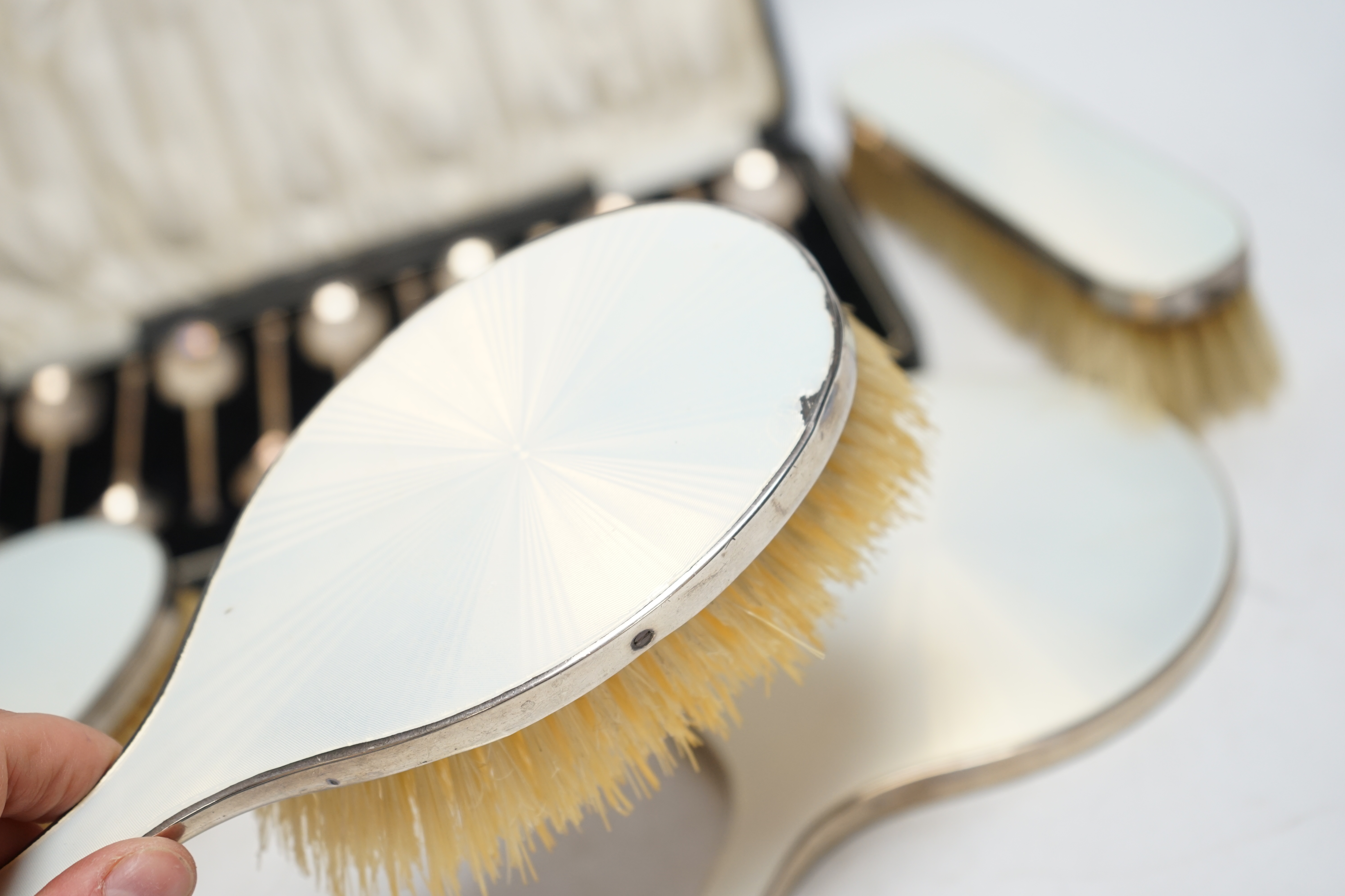 A cased set of twelve George V silver teaspoons, William Suckling Ltd, Birmingham, 1928, 90mm, together with a 1930's silver and enamel mounted for piece mirror and brush set. Condition - poor